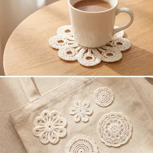 Detailed view of delicate white crocheted lace flower patches on a natural linen bag