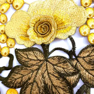Detailed close-up showing golden floral embroidery and green leaves on hollow lace patch