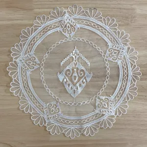 Elegante witte ronde kanten placemat met etnisch borduurwerk op houten ondergrond