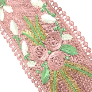 Close-up of pink mesh lace with intricate floral embroidery and gold thread details.