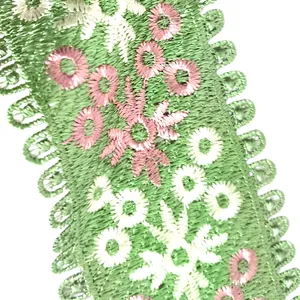 Macro detail of green embroidered floral lace trim with pink and white flowers