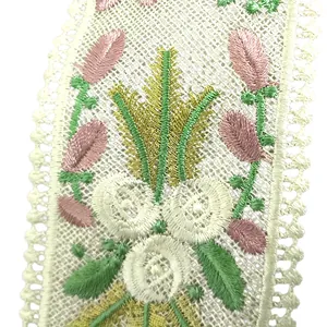 Detailed view of heavy floral embroidery on white lace fabric with pink and green threads.