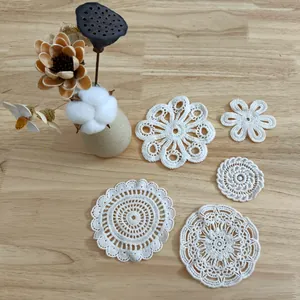 Collection of various white crochet lace coasters and floral embroidery patches on wood