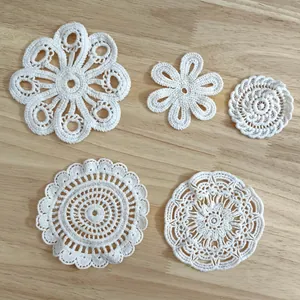 Detailed view showing various patterns of white crochet lace flower patches and coasters