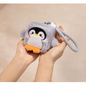 Close-up view of a cute grey square penguin plush pendant held by hands for scale