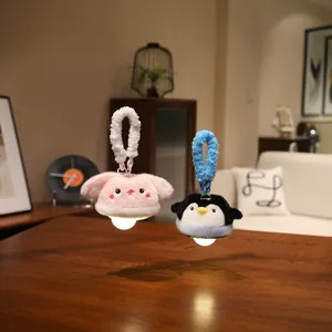 Two cute plush animal night lights, rabbit and penguin, hanging over a dark wooden table.