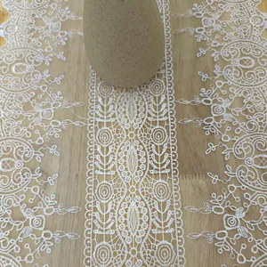 Macro detail showing the intricate embroidery on a French white lace table runner