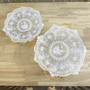 Detailed view of two vintage white lace placemats with floral embroidery on gold stands.