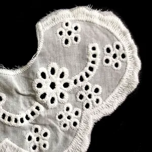 Close-up macro view of white cotton floral eyelet embroidery on a detachable collar.