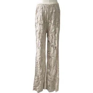 Detailed macro view of beige crochet lace flared trousers with intricate floral patterns