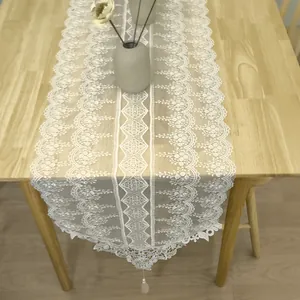 Elegante runner da tavola in pizzo bianco ricamato con motivi floreali e nappe