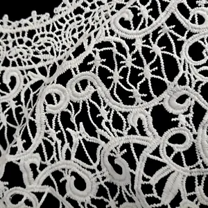 Detailed close-up of intricate white milk silk embroidery lace with hollow floral patterns