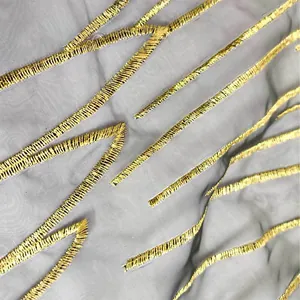 Detailed macro shot showing the fine texture of grey organza with golden metallic embroidery