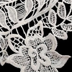 Gros plan sur de la dentelle en soie de lait blanche aux détails floraux brodés