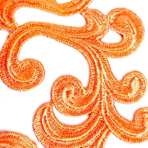 Macro detail of vibrant orange water-soluble embroidery lace with intricate scroll patterns