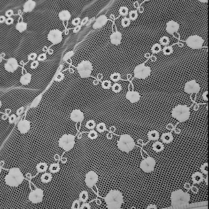 Macro-detailopname van de textuur van witte kant-mesh stof met delicaat geborduurd bloemmotief