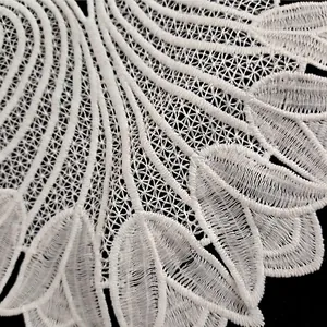Macro della trama di un pizzo ricamato in seta di latte bianca con motivi traforati.
