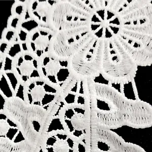 Close-up of white milk silk embroidered lace with intricate hollow flower patterns.