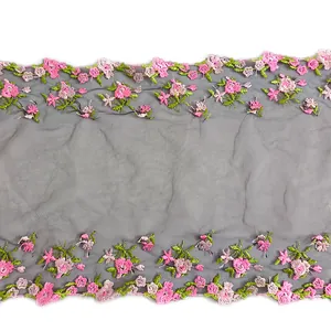 Detailed view of pink floral embroidered lace trim on dark mesh for DIY sewing.
