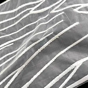 Close-up detail of white wing embroidery on sheer organza lace fabric for DIY sewing