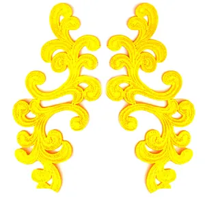 Macro detail of yellow symmetrical scroll embroidery lace applique for DIY sewing.