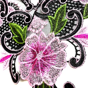 Close-up macro detail of high-quality pink floral embroidery on black mesh lace