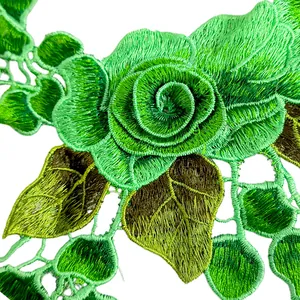 Dettaglio macro del colletto in pizzo ricamato con rosa verde e cuciture fini