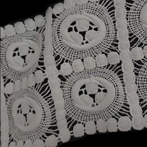 Macro detail of white water-soluble embroidered milk silk lace with hollow floral pattern.
