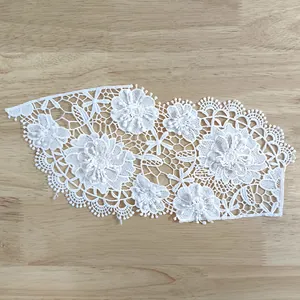 High detail view of intricate 3D white floral embroidery lace applique for apparel.