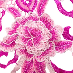 Gros plan sur un détail d'applique en dentelle brodée de fleurs 3D rose et violet