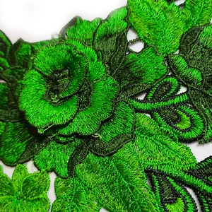 Gros plan d'un col en dentelle brodée vert avec des détails de fils complexes.