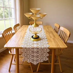 Intricate white lace table runner with hollow floral embroidery on a wooden dining table