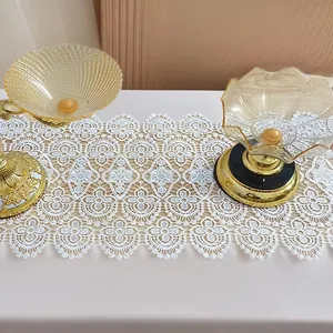 Detail view of elegant white hollowed-out lace table runner with intricate embroidery