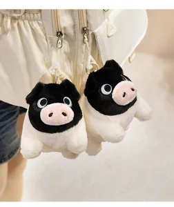 Detailed view of two cute black and white pig plush keychains hanging on a bag