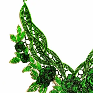 Detaillierte Nahaufnahme der aufwendigen grünen Blumenstickerei auf weißem Spitzenstoff.