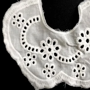 Detailed macro view of white cotton eyelet embroidered doll collar with floral lace pattern