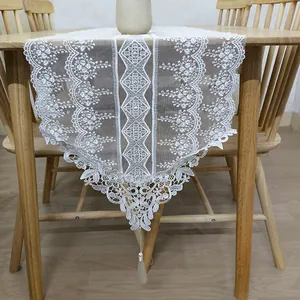 Elegante runner da tavola in pizzo ricamato bianco in stile francese con nappa su tavolo legno