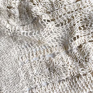 Vista macro dettagliata del tessuto a maglia traforata beige con motivi all'uncinetto