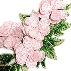 Macro detail of a 3D multi-layered pink embroidered flower lace patch with green leaves.