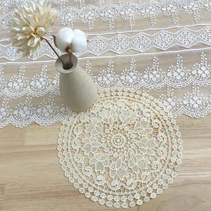Detalle de un posavasos redondo de encaje beige bordado con diseño floral vintage
