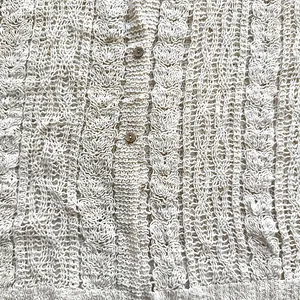 Macro dettagliata del tessuto a maglia traforata in crema con i bottoni in legno.