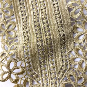 Detailed macro view of intricate gold embroidery thread on elegant hollow lace fabric.