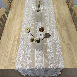 Elegante runner da tavola in pizzo ricamato bianco su un tavolo da pranzo in legno