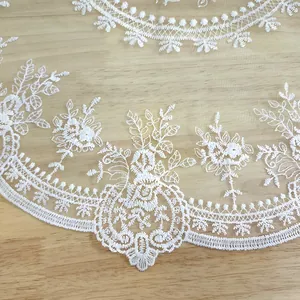 Close-up of elegant white vintage lace placemat with floral embroidery on transparent mesh fabric