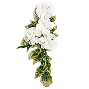 Detail view of 3D embroidered floral lace patch with white flowers and green leaves