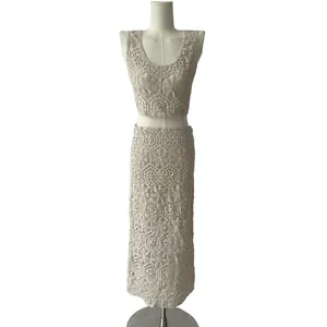 Detailed macro view of the intricate beige cotton crochet lace embroidery on the skirt.