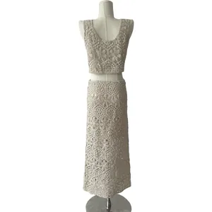 Back view of elegant cream crochet knit two-piece set featuring lace crop top and long skirt