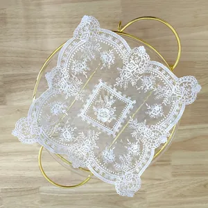 Detail view of white vintage lace placemat with intricate floral embroidery on a gold tray