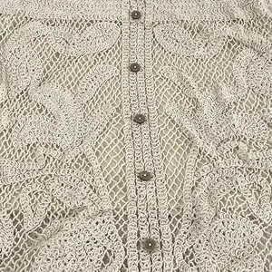Detailed macro view of cream floral crochet lace fabric texture with dark vintage buttons