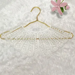 Macro detail of the intricate white embroidered lace pattern on a large false collar